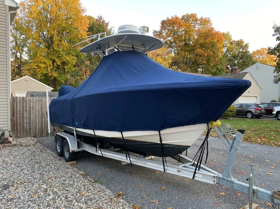 Center-console boat under a fitted navy cover on a trailer